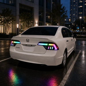 This nighttime scene shows a white 2006–2011 Honda Civic sedan fitted with PRISMBEAM RGB tail lights. The mirrored multicolor light signatures and subtle reflections are visible on the wet parking-lot pavement.