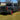 2019-2023 Chevrolet Silverado modified pickup truck featuring smoked red LED taillights, off-road tires, and red wheels, parked on outdoor grass