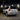 A white 2010 Lexus GX460 is shown from the rear three-quarter angle outside an industrial building at night. Its illuminated red and amber PRISMBEAM tail lights reflect subtly across the glossy body and pavement.