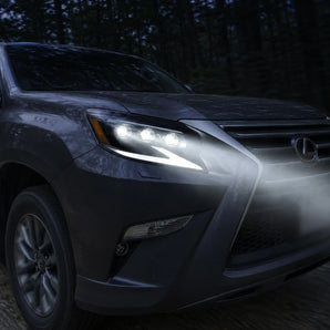 2014-2019 Lexus GX460 with PRISMBEAM triple projector LED headlights on a forest road at dusk