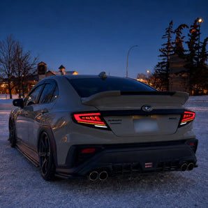 This winter twilight scene shows a 2022–2026 Subaru WRX from the rear three-quarter angle. Its red C-shaped light guides, amber strips and white reverse-light sections remain clearly visible against the snow.
