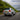 Silver Toyota Land Cruiser with illuminated PRISMBEAM LED tail lights driving along a forest road.
