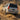 A silver Lexus GX 470 is shown from a rear three-quarter angle while driving through sand. Its symmetrical LED tail lights display red outer signatures, amber inner light strips, and illuminated lower amber bars against a dramatic dust plume.