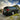 Silver Toyota Land Cruiser with illuminated PRISMBEAM LED tail lights in a mountain grassland rear view.